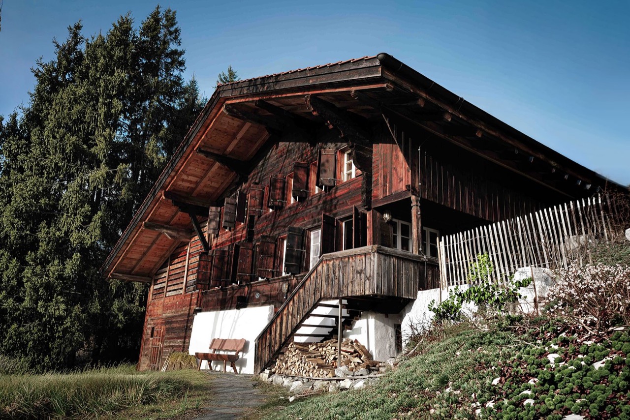 Chalet Amalia traditional Simmentaler timber facade with firewood store under blue summer sky
