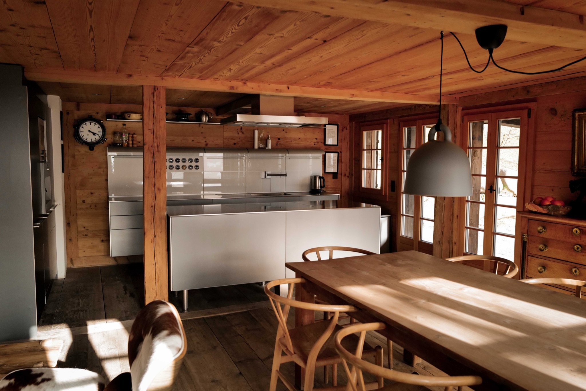 Open kitchen and dining area inside Chalet Amalia, Wishbone chairs and warm timber bathed in Alpine light