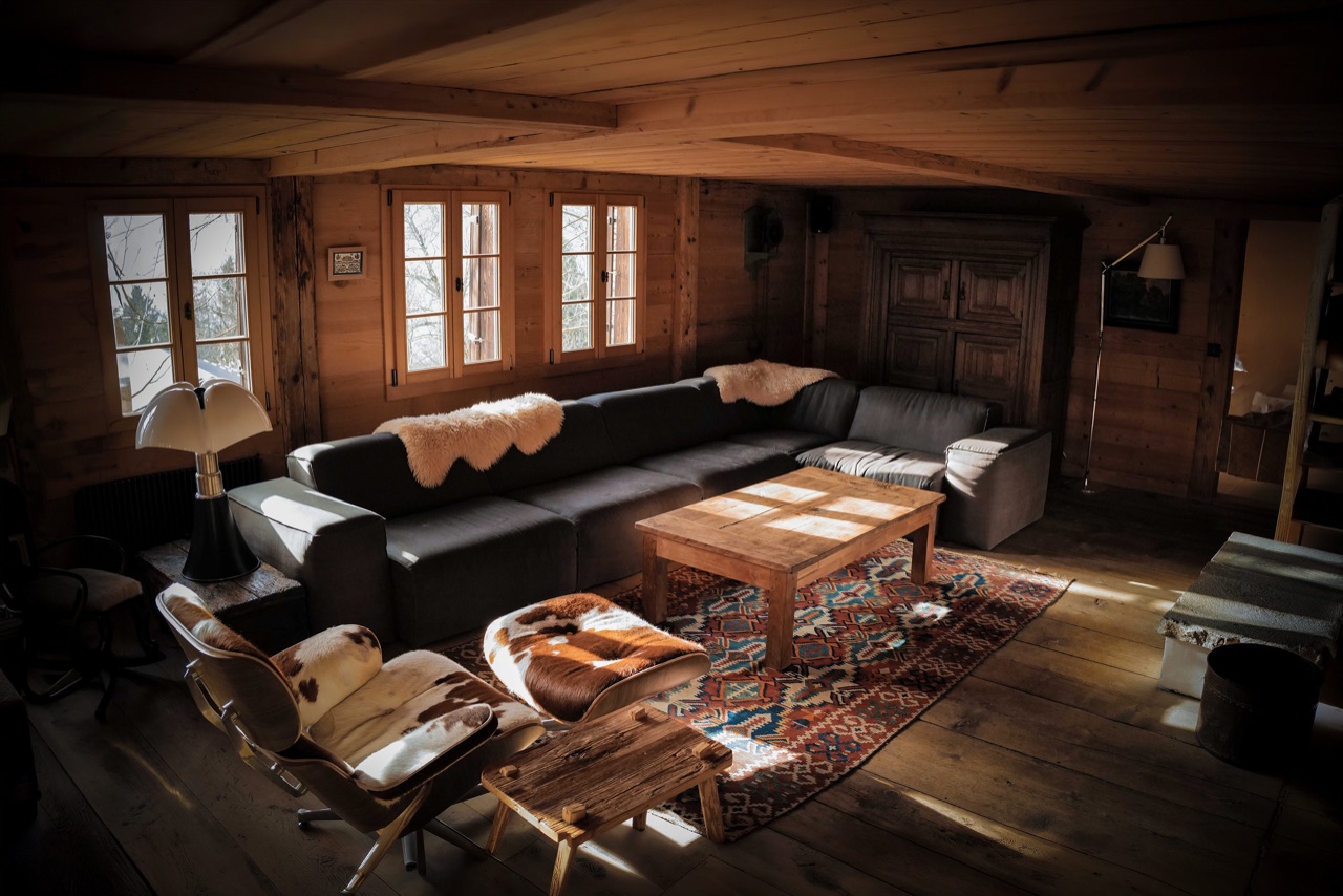 Living room with leather sofas, Eames lounge chair and kilim rug bathed in Alpine light