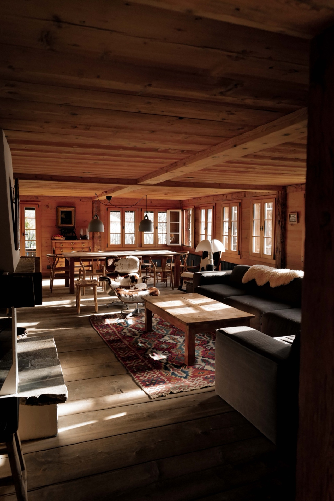 Open-plan living and dining area seen through a timber doorway with warm light across the floors