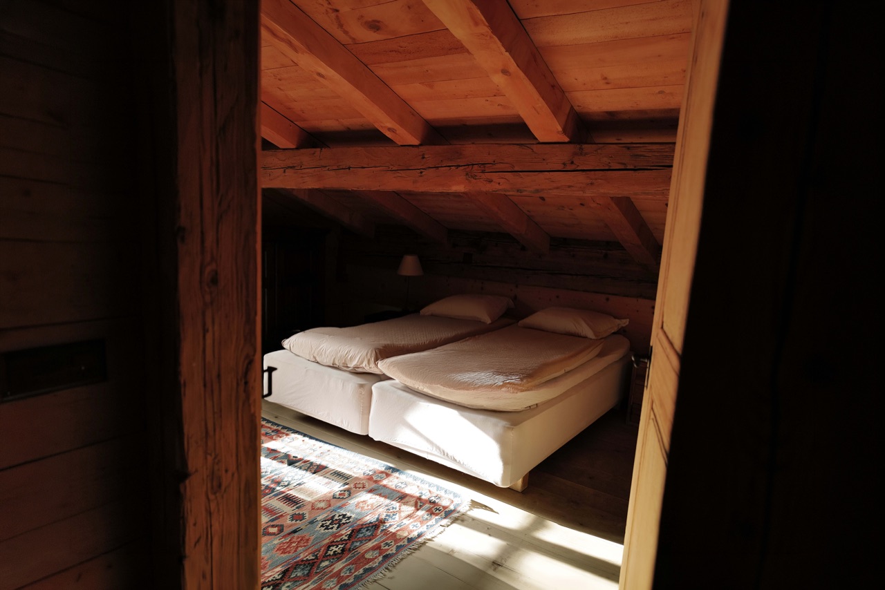 Cozy attic bedroom seen through a timber doorframe with kilim rug