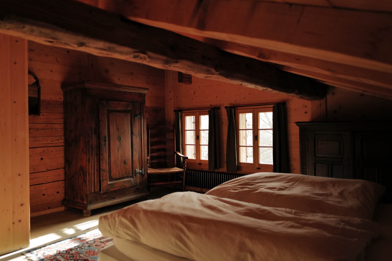 Attic bedroom with antique wardrobe, exposed beams and morning light