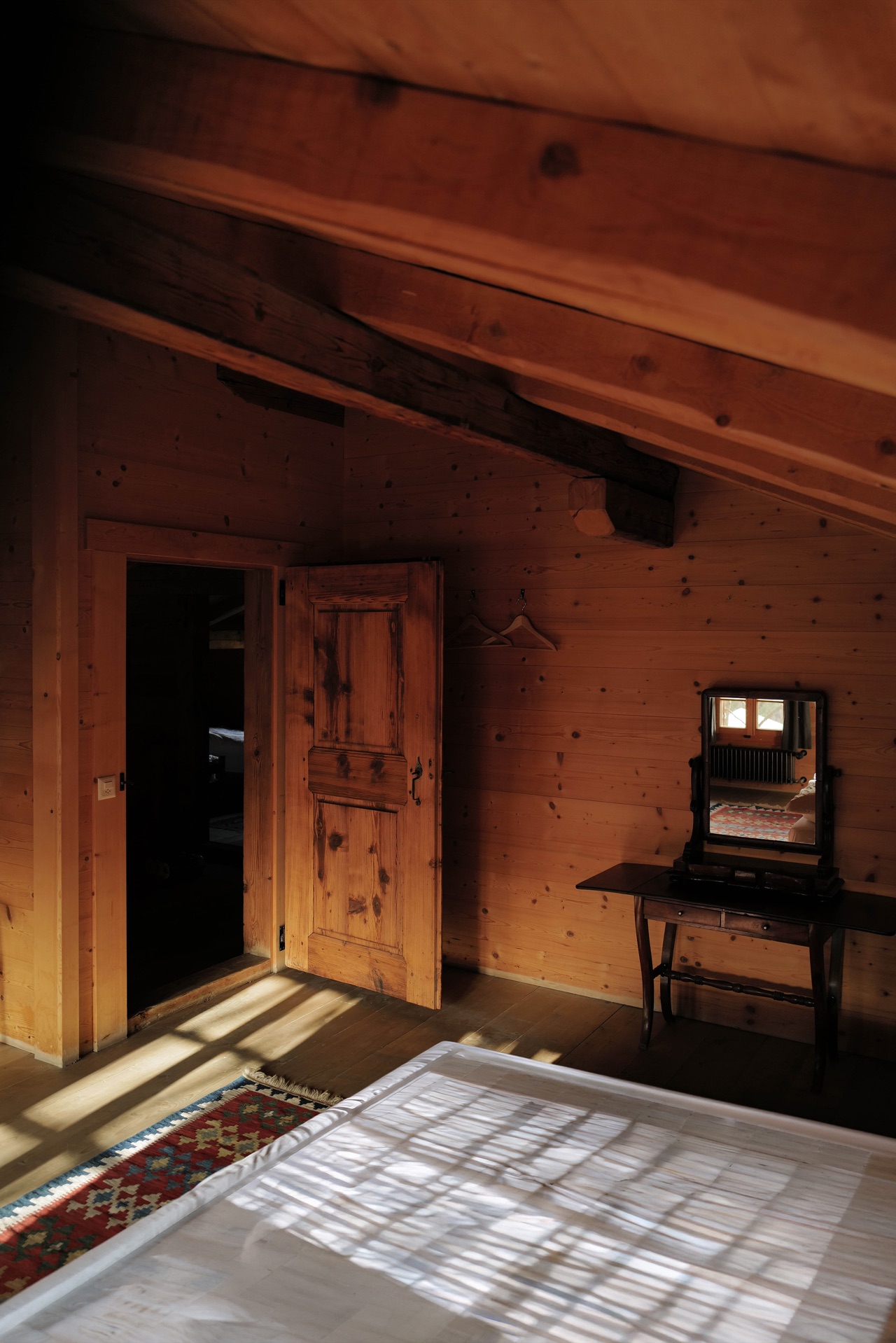 Bedroom with antique vanity mirror, timber door and dappled sunlight