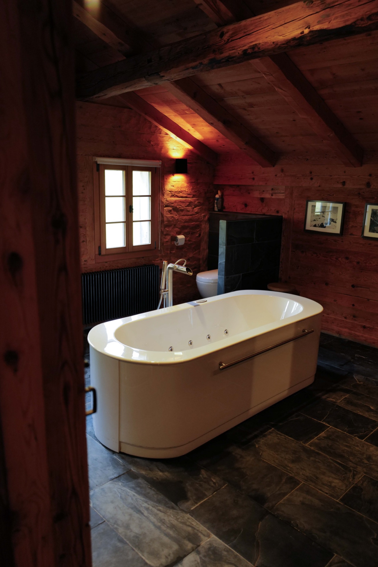Freestanding whirlpool bathtub under exposed beams with slate floor