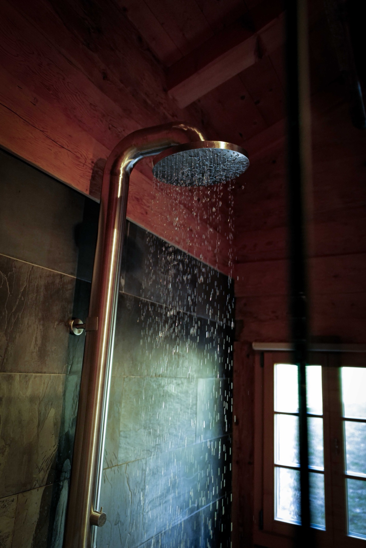 Brass rain shower head with running water and warm ambient light