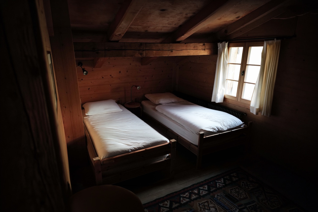 Twin bedroom with wooden beds and curtained window