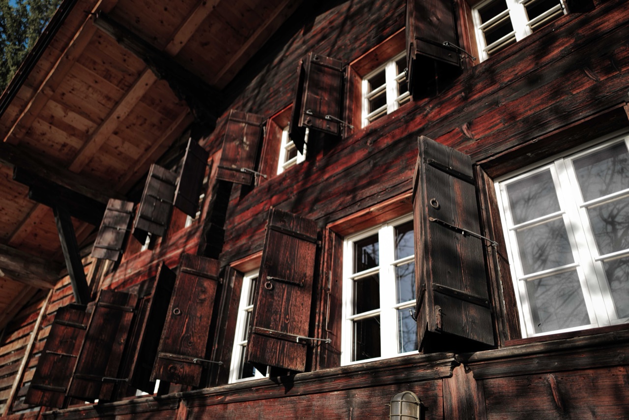 Traditional Simmentaler facade with dark timber and open wooden shutters