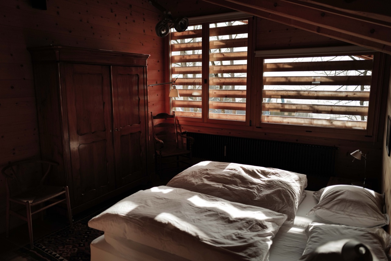 Bedroom with antique wardrobe and light streaming through wooden shutters